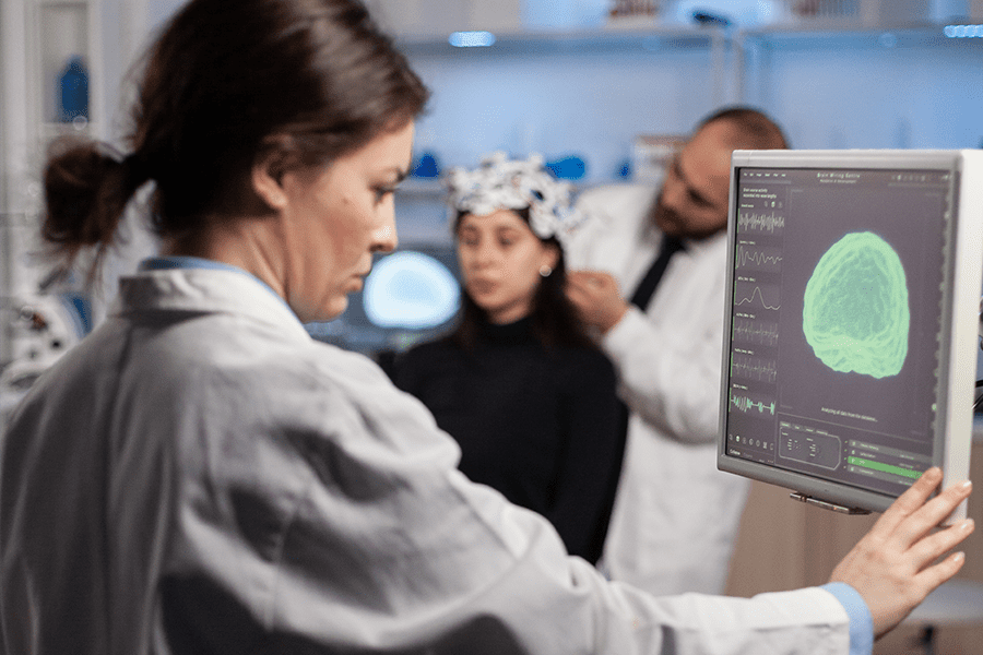 A physician examines a brain scan on a monitor while performing deep brain stimulation on a patient