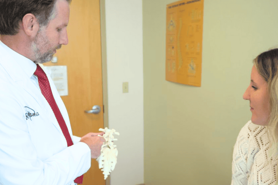 Ryan F. Moncman, D.O. explaining spinal stenosis with a model spinal column to a patient