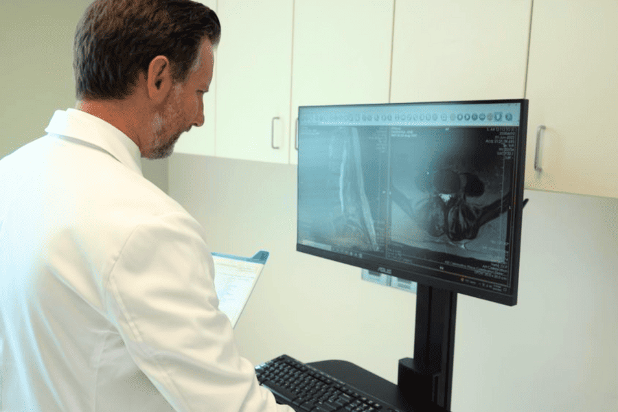 Ryan F. Moncman, D.O. reviewing scan of a patient's spine