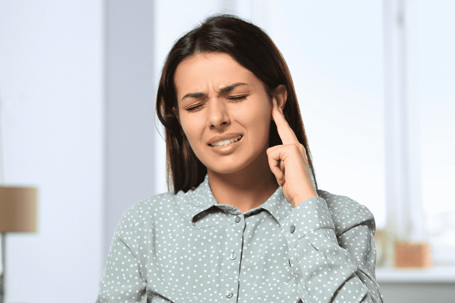 woman holding fingers to ear with nerve pain